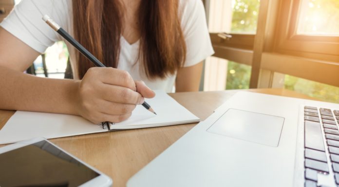 Etudiante travaille à l'écrit devant son ordinateur et son téléphone